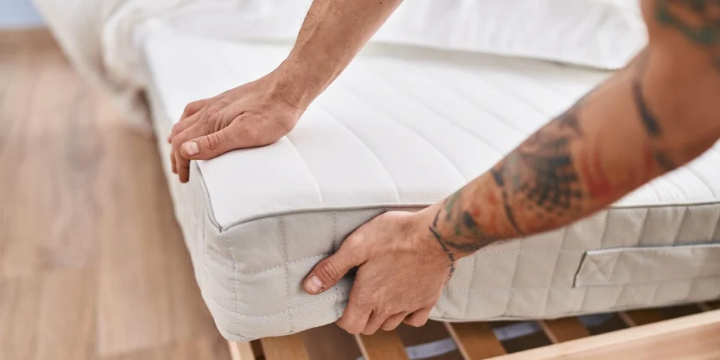 personne qui remet en place son matelas sur le sommier